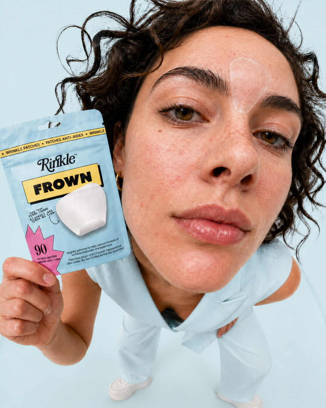 Person holding a Rinkle Frown product against a light blue background
